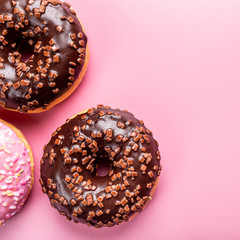 Overhead shoot of colorful donuts on pink background with mint. Birthday party food concept with copy space. Top view
