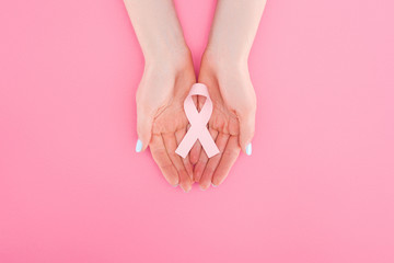 partial view of woman with pink breast cancer sign on pink background