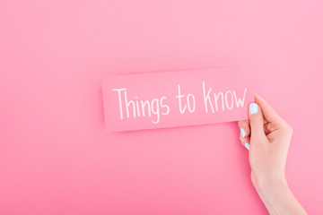partial view of woman holding card with things to know lettering on pink background