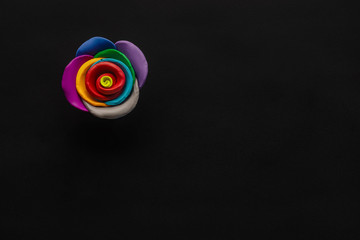 A flower made from plasticine on black background , shot from above, aligned at the top left.