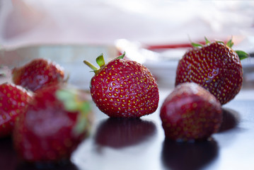 Ripe strawberries with leaves in wicker basket on table on blurred background
