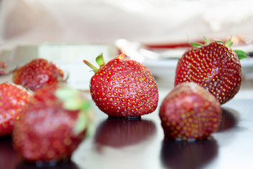 Ripe strawberries with leaves in wicker basket on table on blurred background