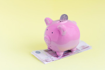 pink piggy Bank and money on a yellow background, the concept of accumulation and multiplication of money