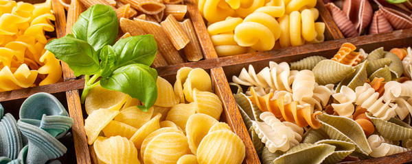 Spaghetti and assorted colorful italian pasta in wooden box. Healthy food background concept. Flat...