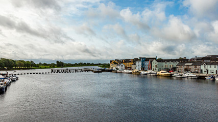 Beautiful view of the river Shannon with boats anchored on the coast and picturesque houses in the Athlone town, wonderful cloudy day in the county of Westmeath, Ireland