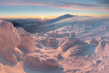 Beautiful winter panorama with fresh snow and hoarfrost. Landscape with spruce trees with sun light mountains on background Fantastic evening winter landscape. Dramatic colorful sky. Beauty world.