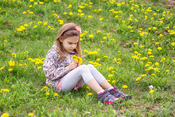 Girl and dandelions / Lovely little girl playing in the spring field full of dandelions