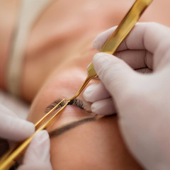 Procedure of eyelash extension in salon by cosmetician