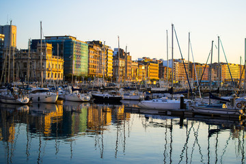 Sunset in the dock of Gijon, Asturias, Spain. Reflections of the boats in the water