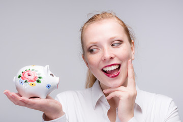 Fototapeta na wymiar happy young red haired woman with her piggy bank