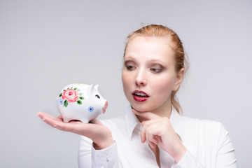 Fototapeta na wymiar young red haired woman happy with her piggy bank