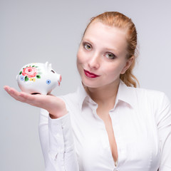 Fototapeta na wymiar young red haired woman presents her piggy bank