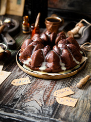 Delicious homemade chocolate bundt cake on wooden plate stands on rustic table
