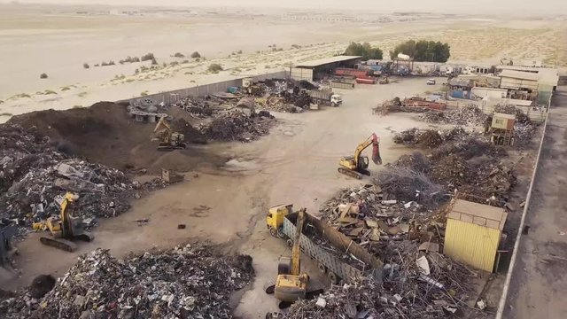 Fly towards scrap yard with excavators and dump trucks (4K)
