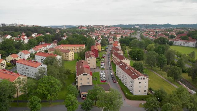 Aerial video of many apartment buildings in the suburb Orgryte torp in Gothenburg, Sweden, with lots of green bushes and trees around them and the skyline in the background