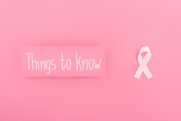 top view of card with things to know lettering and breast cancer sign on pink background