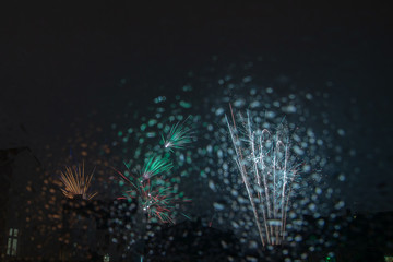 Obraz premium New years eve fireworks seen trough a roof window pane full of raindrops
