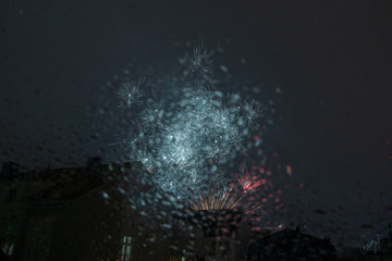 New years eve fireworks seen trough a roof window pane full of raindrops