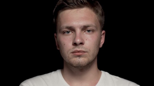 Head of caucasian man looking at camera with arms folded. Black background.