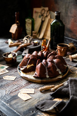 Delicious homemade chocolate bundt cake on wooden plate stands on rustic table