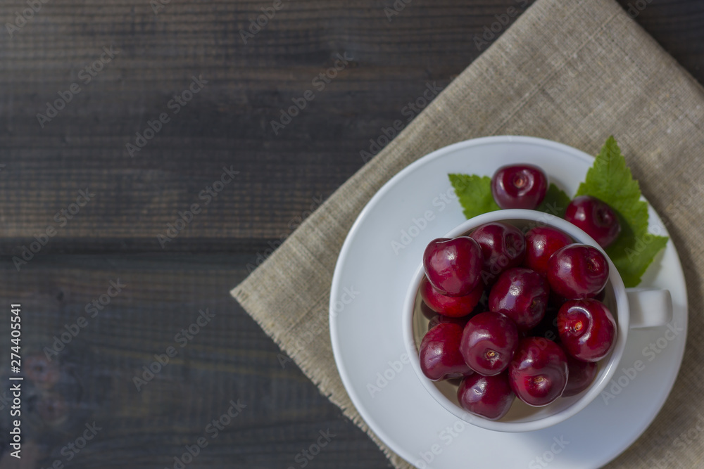 Wall mural fresh organic ripe sweet cherry in a white ceramic mug