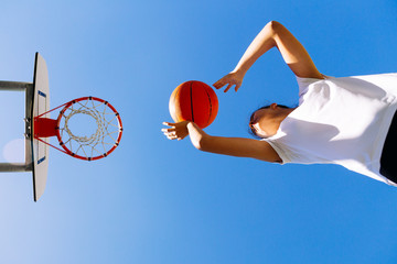 Young girl shooting basket outdoors