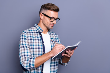 Close up photo handsome he him his guy hands arms hold notebook making notes author have inspiration clever smart creative ideas wear specs casual plaid checkered shirt isolated grey background