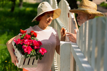 Neighbors standing near fence talking about planting flowers