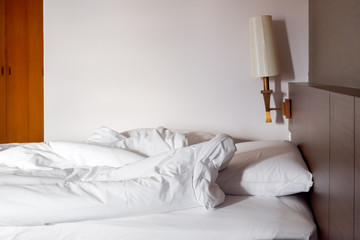 White crumpled bed sheet and messy pillows in a hotel room