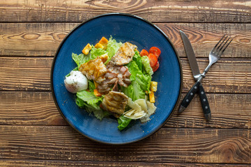 The hot salad with meat on a wooden background.
