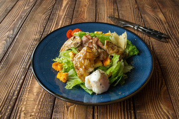 The hot salad with meat on a wooden background.