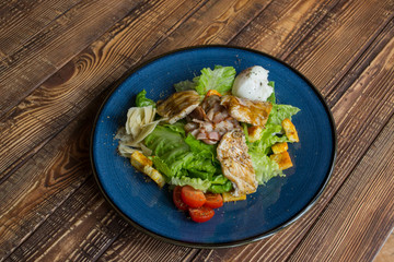 The hot salad with meat on a wooden background.