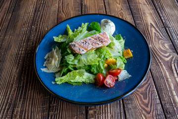 The salad with salmon on a wooden table.
