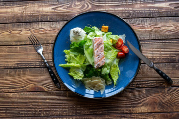 The salad with salmon on a wooden table.