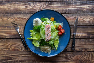 The salad with salmon on a wooden table.