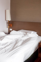 White crumpled bed sheet and messy pillows in a hotel room