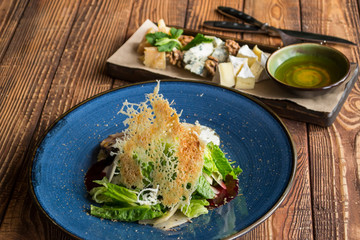 The hot salad with meat, and cheese plate on a wooden table.
