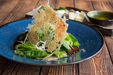 The hot salad with meat, and cheese plate on a wooden table.