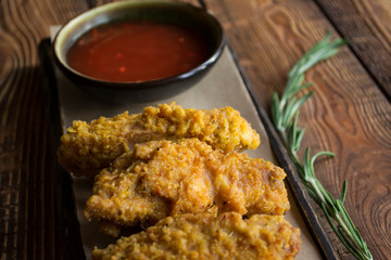 Fried chicken with sauce on a wooden table.