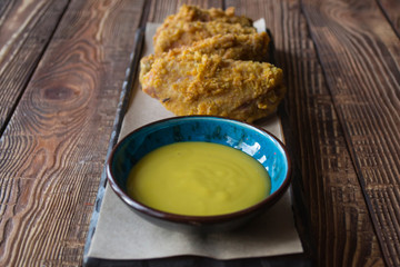 Fried chicken with sauce on a wooden table.