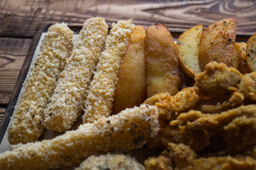 Fried potatoes with fish, cheese sticks and sauces.