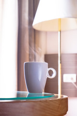 one cup hot coffee with smoke on the glass table in the window light in room