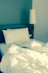 White crumpled bed sheet and two messy pillows in a hotel room