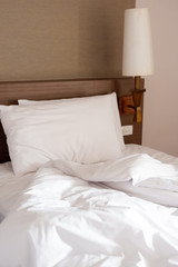 White crumpled bed sheet and two messy pillows in a hotel room