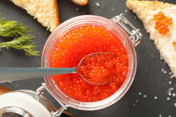 Composition with caviar in glass jar, bread, spoon and cutting board, top viewComposition with caviar in glass jar, bread, spoon and cutting board, top view