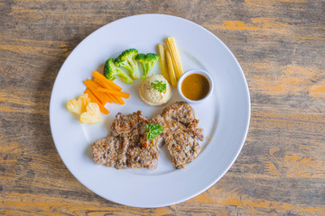 Pork steak with vegetable salad on a white plate.