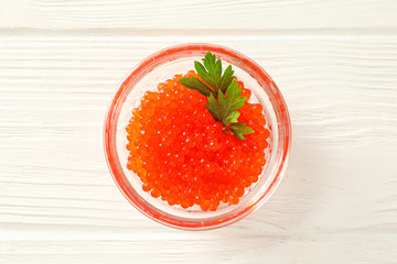 Glass jar with red caviar isolated on white wooden table, space for text