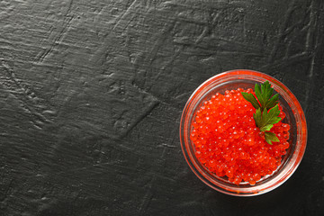 Glass jar with caviar on black background, space for text