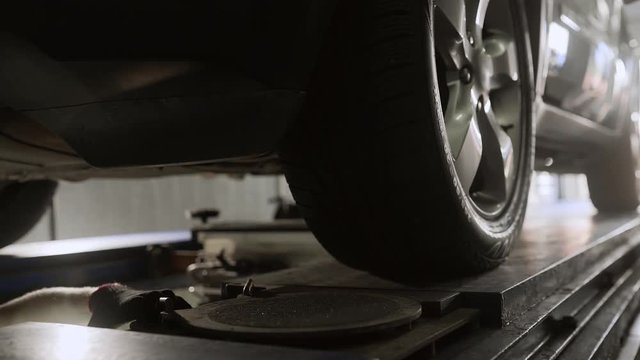 Mechanic moves and prepares car on the service stand for wheel alignment, car station, suspension repair, vehicle pit, Full HD Prores 422 HQ