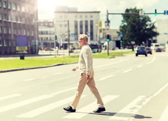 Fototapeta premium leisure and people concept - senior man walking along summer city crosswalk